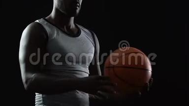 黑人运动员双手提着篮子球，思考着比赛策略